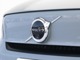 【ボルボの電気自動車を象徴するフロントフェイス】時代に合わせて変化するエンブレムデザイン。センターを斜めに大きく横切るラインと黒地に銀のアイアンマーク、これが最新ボルボのキャラクターアイコンです。